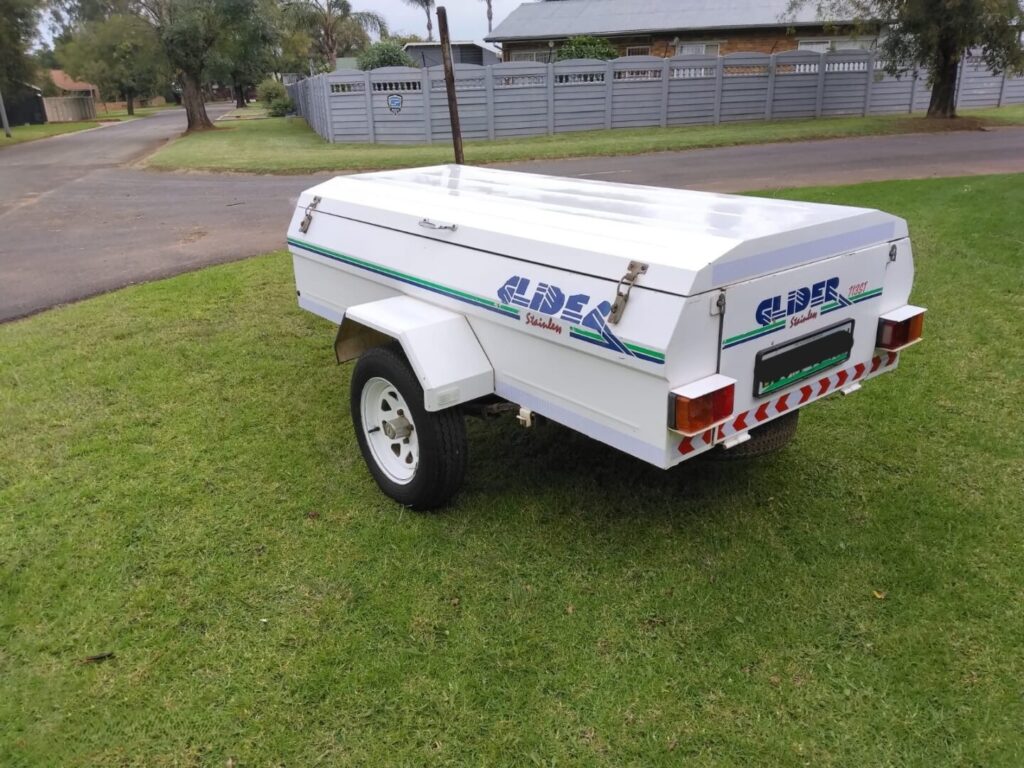Rear side view of white Glider trailer on grass